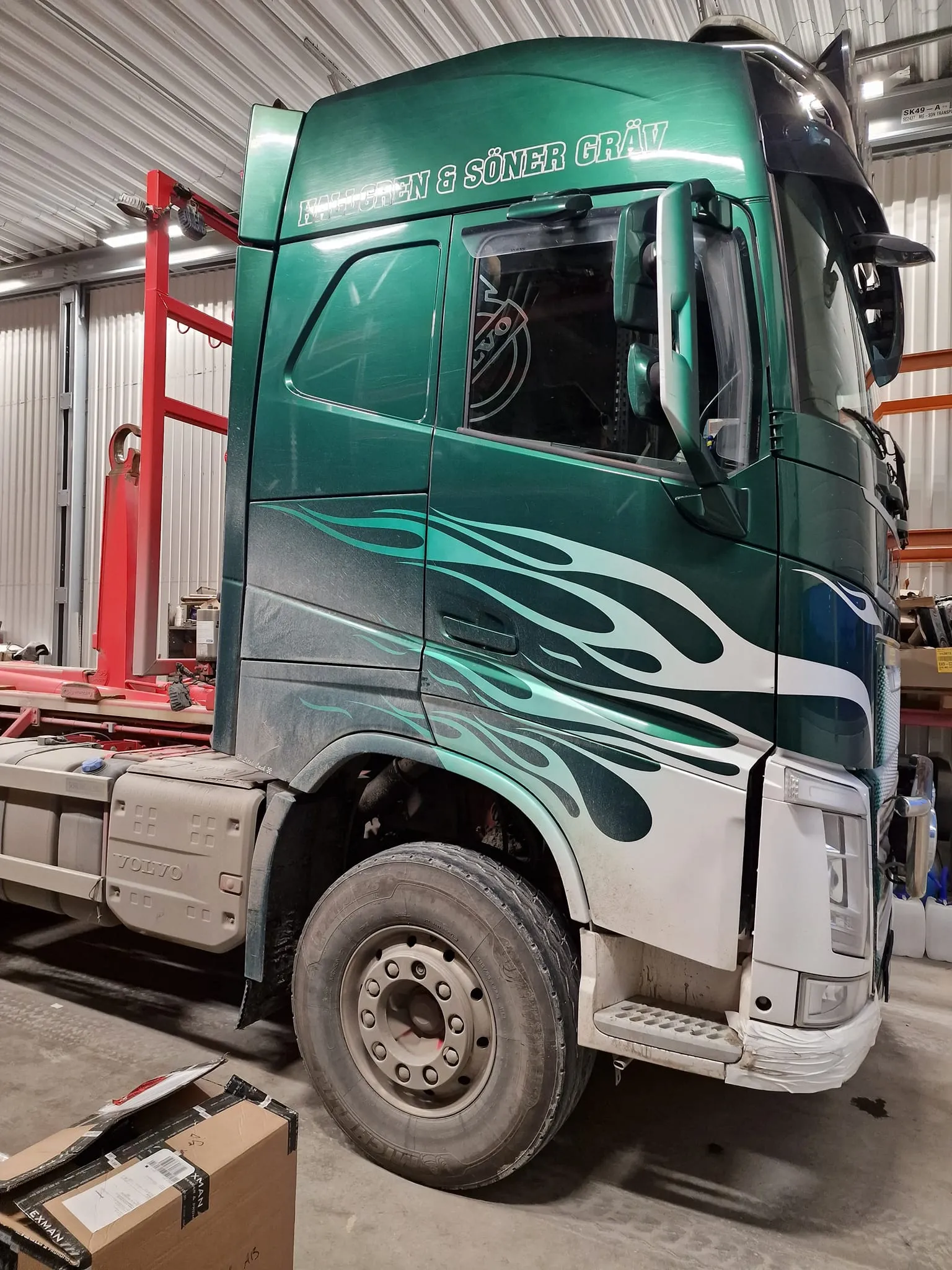 Grön Volvo-lastbil med flamdesign i verkstad